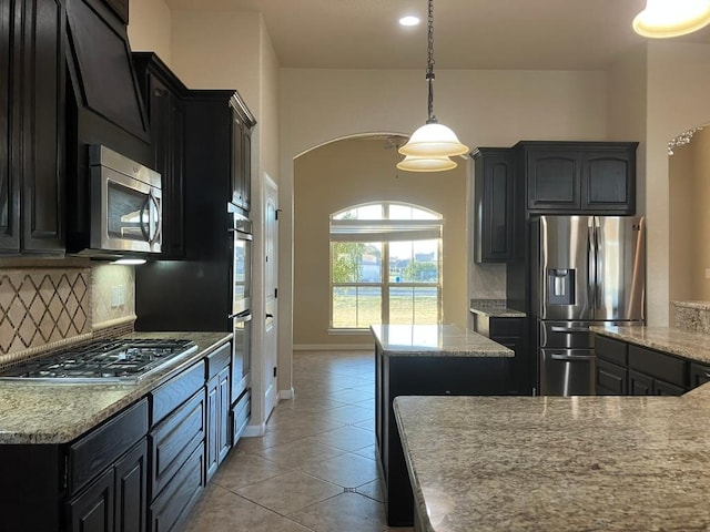 129 S Abrego Xing, Floresville, TX 78114 - kitchen featuring appliances with stainless steel finishes, tasteful backsplash, dark cabinetry, arched walkways, and recessed lighting