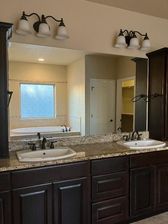 129 S Abrego Xing, Floresville, TX 78114 - full bathroom featuring a sink, a garden tub, and a closet