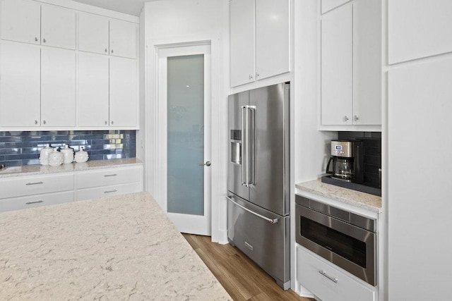 301 Eocene, Horseshoe Bay, TX 78657 - kitchen featuring appliances with stainless steel finishes, decorative backsplash, white cabinetry, and wood finished floors