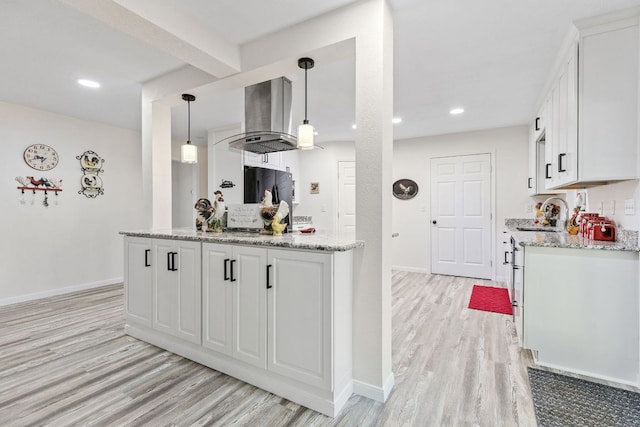 kitchen featuring wall chimney range hood, light wood-type flooring, white cabinetry, baseboards, and recessed lighting