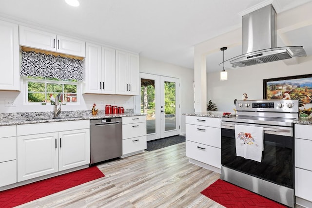 kitchen with appliances with stainless steel finishes, island range hood, a sink, french doors, and light wood-type flooring