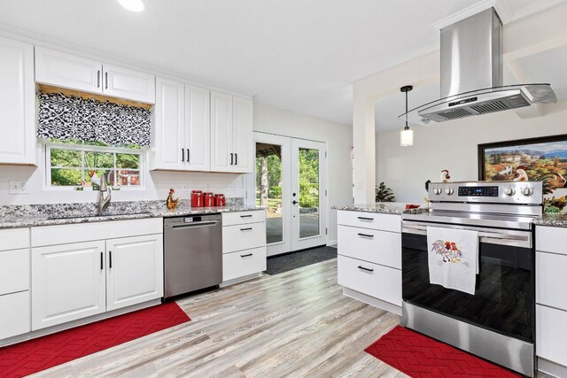 969 N State Highway 95, Bastrop, TX 78602 - kitchen featuring stainless steel appliances, island range hood, french doors, light wood-style flooring, and white cabinets