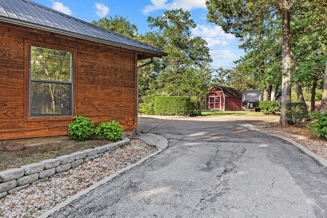 view of side of property with a storage shed, an outbuilding, and metal roof