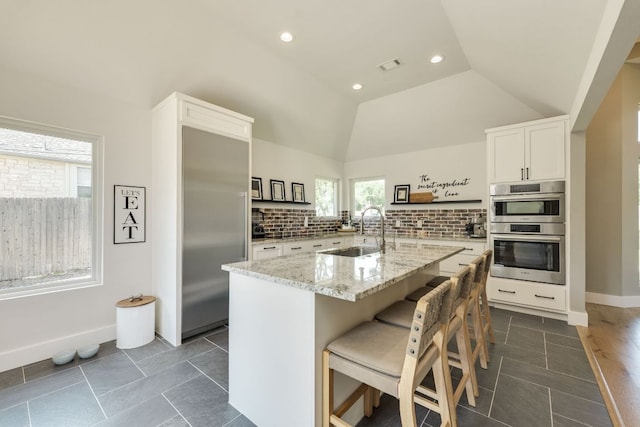1305 Quail Ravine, Round Rock, TX 78664 - kitchen with a sink, light stone countertops, backsplash, white cabinets, and lofted ceiling