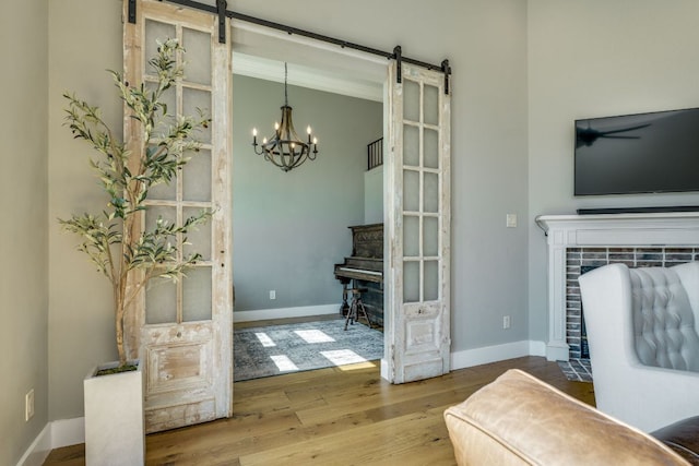 1305 Quail Ravine, Round Rock, TX 78664 - living room featuring a barn door, wood finished floors, a chandelier, and baseboards