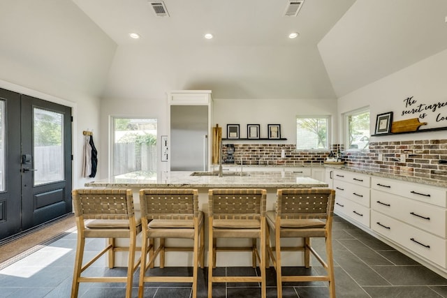 1305 Quail Ravine, Round Rock, TX 78664 - kitchen featuring a sink, light stone countertops, french doors, white cabinets, and decorative backsplash