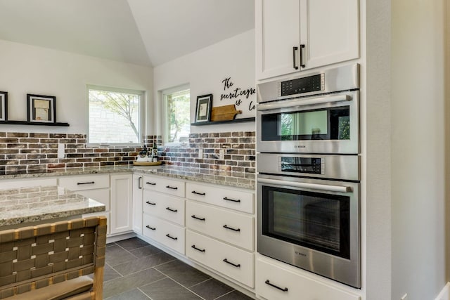 1305 Quail Ravine, Round Rock, TX 78664 - kitchen with double oven, tasteful backsplash, light stone countertops, vaulted ceiling, and white cabinets
