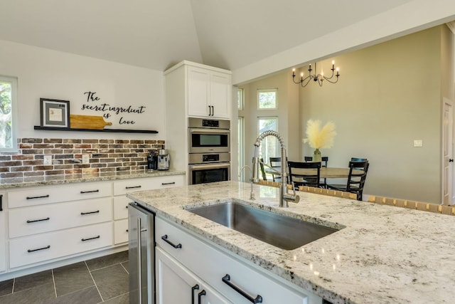 1305 Quail Ravine, Round Rock, TX 78664 - kitchen with a sink, stainless steel double oven, a chandelier, white cabinetry, and light stone counters