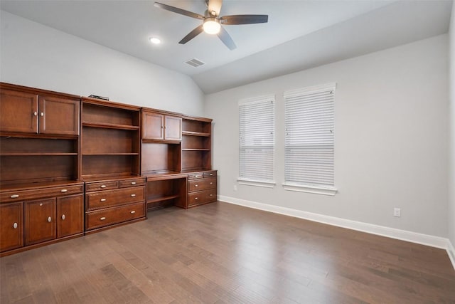 unfurnished office featuring dark wood finished floors, lofted ceiling, a ceiling fan, baseboards, and built in study area