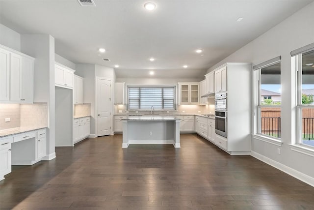 kitchen featuring backsplash, dark wood finished floors, a kitchen island, white cabinets, and recessed lighting