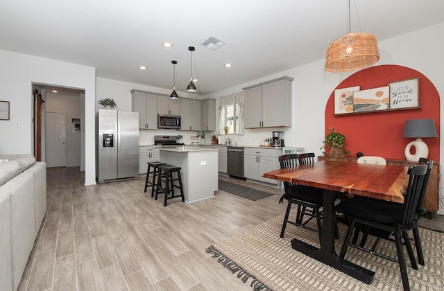 500 Pickrell Loop, Liberty Hill, TX 78642 - kitchen featuring appliances with stainless steel finishes, gray cabinets, light countertops, a center island, and a kitchen bar