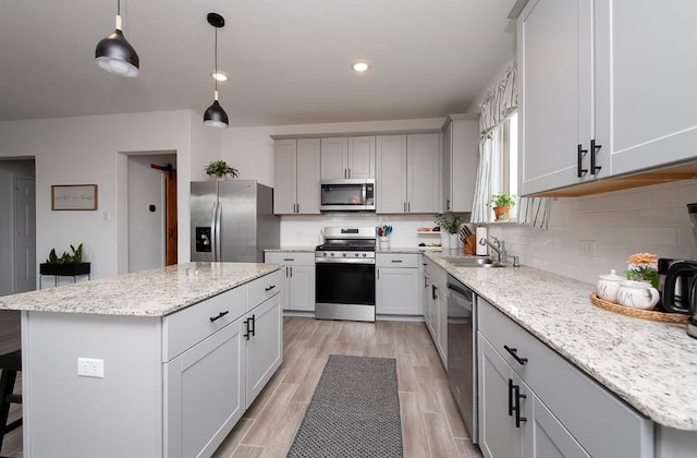 500 Pickrell Loop, Liberty Hill, TX 78642 - kitchen with stainless steel appliances, a sink, a center island, gray cabinetry, and light wood finished floors