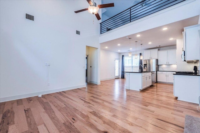 kitchen featuring dark countertops, ceiling fan, light wood-type flooring, white cabinets, and recessed lighting