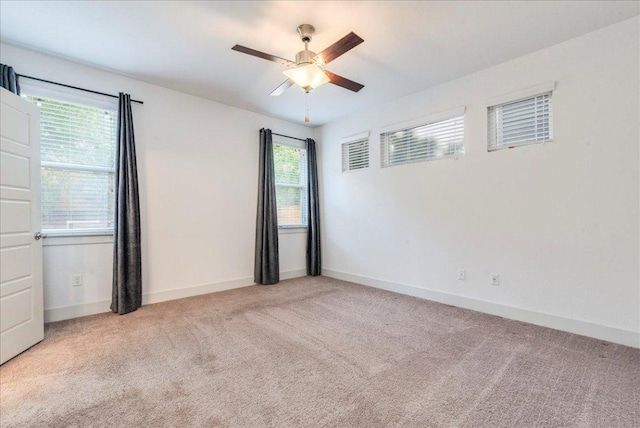 carpeted spare room featuring a ceiling fan and baseboards
