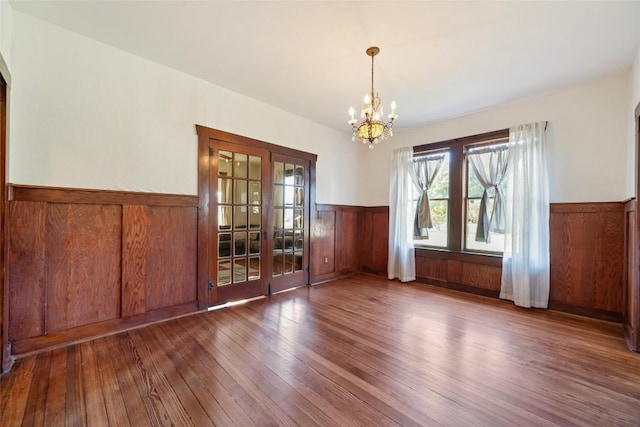 117 N Main St, Paige, TX 78659 - unfurnished dining area featuring wainscoting, a chandelier, wood-type flooring, and wooden walls