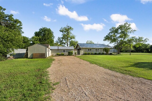 117 N Main St, Paige, TX 78659 - single story home featuring a storage shed, driveway, a front yard, an outdoor structure, and metal roof