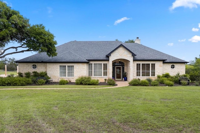 420 Oak Forest Dr, Buda, TX 78610 - french country home with stone siding, a chimney, a front lawn, and a shingled roof