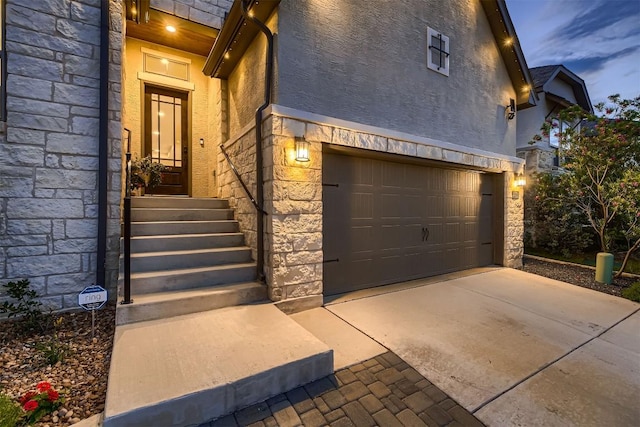 property entrance with stone siding, a garage, and stucco siding