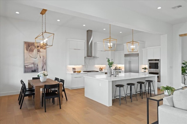 1754 County Road 146th Rd, Georgetown, TX 78633 - kitchen with stainless steel appliances, wall chimney range hood, a chandelier, a breakfast bar, and tasteful backsplash