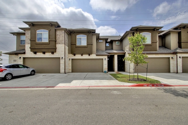 view of property featuring an attached garage, stucco siding, and driveway