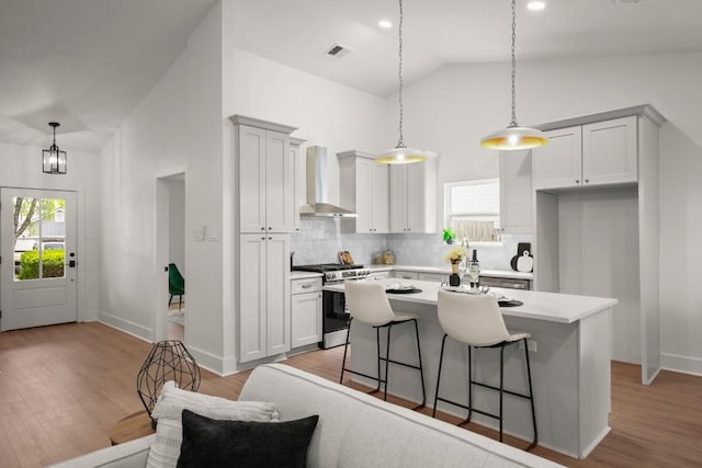 1417 Charolais Dr, Austin, TX 78758 - kitchen with wall chimney range hood, stainless steel gas range oven, vaulted ceiling, a center island, and decorative backsplash
