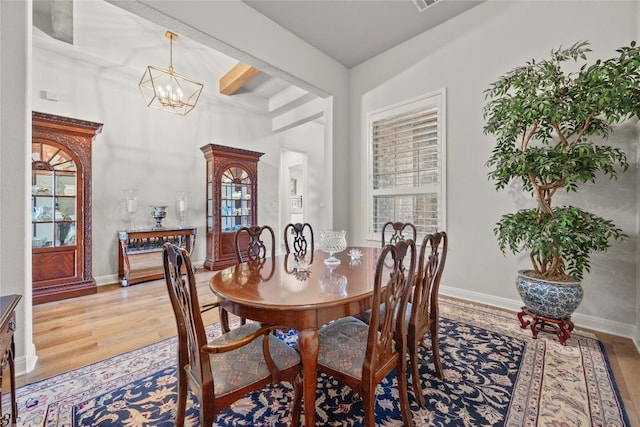 dining room with light wood finished floors, a chandelier, and baseboards