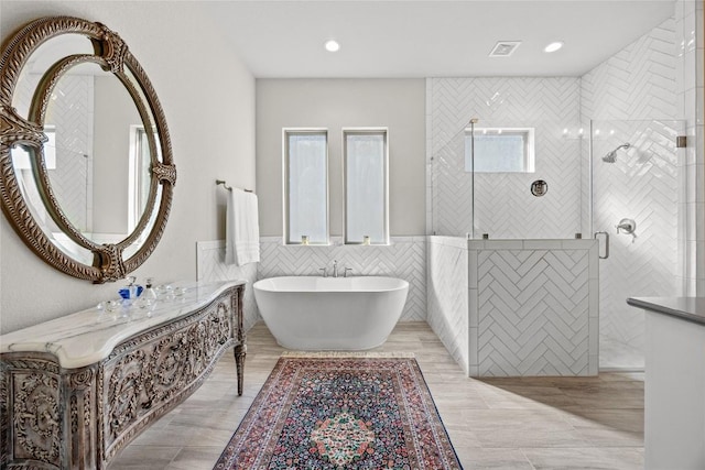 2032 Murano Ln, Leander, TX 78641 - bathroom featuring tile walls, a soaking tub, a shower stall, vanity, and wainscoting