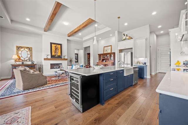 2032 Murano Ln, Leander, TX 78641 - kitchen with blue cabinets, open floor plan, white cabinets, light wood-style floors, and stainless steel fridge