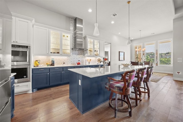 2032 Murano Ln, Leander, TX 78641 - kitchen with wall chimney exhaust hood, stainless steel double oven, light wood finished floors, white cabinets, and recessed lighting