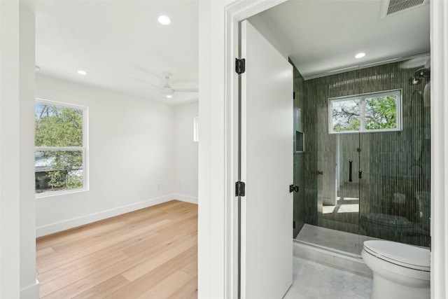 bathroom with toilet, recessed lighting, a stall shower, baseboards, and wood finished floors