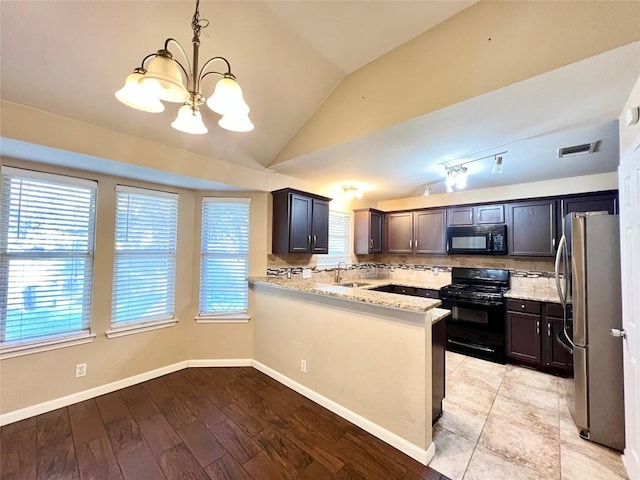 kitchen featuring black appliances, a chandelier, light stone counters, vaulted ceiling, and tasteful backsplash