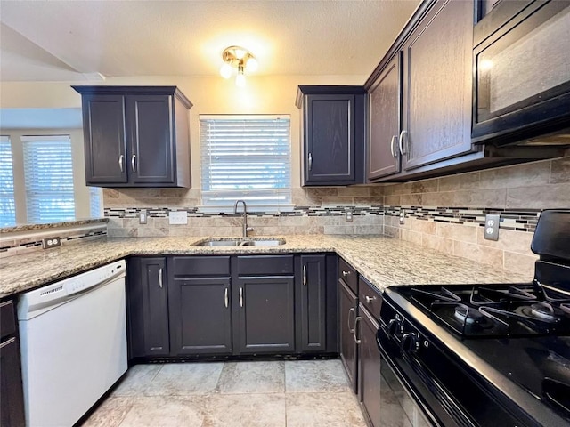 kitchen featuring black appliances, a sink, decorative backsplash, and light stone countertops