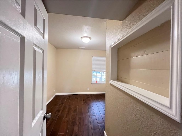 hall featuring dark wood-style flooring and baseboards