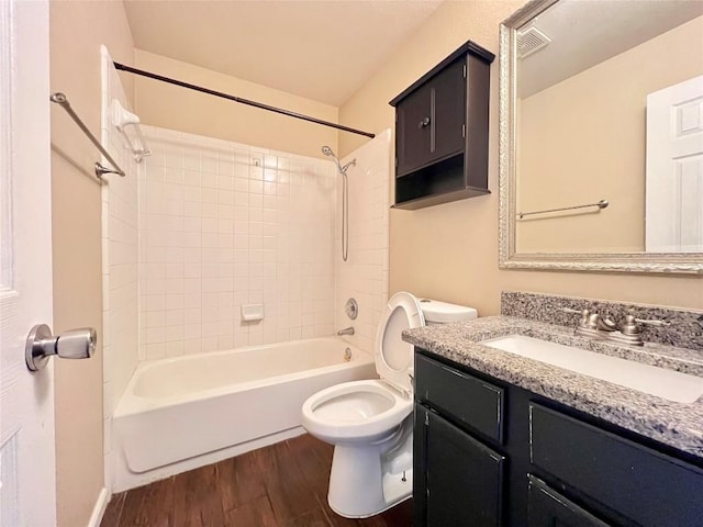bathroom featuring wood finished floors, toilet, vanity, and shower / bathtub combination