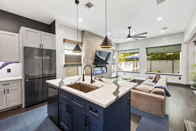 1111 Walton Ln Unit 2, Austin, TX 78721 - kitchen featuring appliances with stainless steel finishes, a sink, open floor plan, light countertops, and dark wood-style floors
