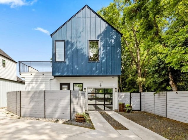 1111 Walton Ln Unit 2, Austin, TX 78721 - view of front of property featuring board and batten siding, a fenced front yard, a gate, concrete driveway, and a balcony