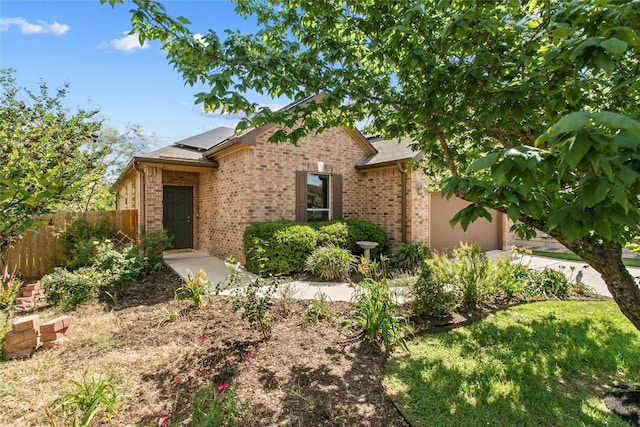 6212 Bumpstead Dr, Austin, TX 78747 - view of front of home with brick siding, roof mounted solar panels, fence, a garage, and concrete driveway
