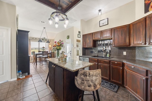 401 Southern Dr, Buda, TX 78610 - kitchen featuring decorative backsplash, dark tile patterned floors, a center island, and vaulted ceiling