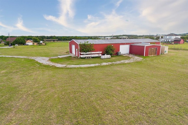 401 Southern Dr, Buda, TX 78610 - view of green lawn with a pole building, a detached garage, driveway, and an outbuilding