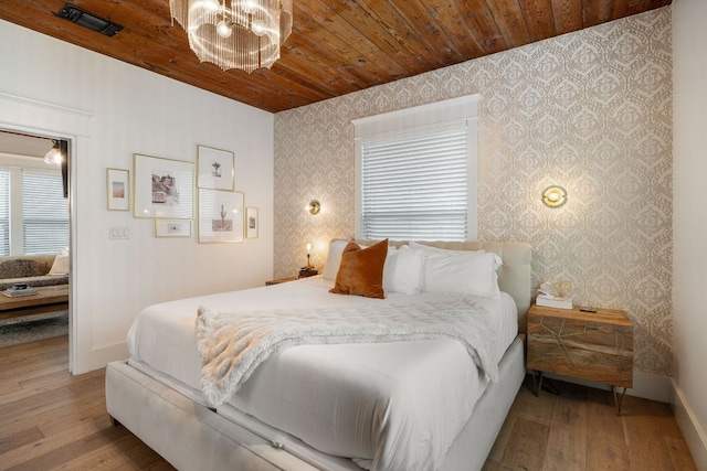 1307 E 2nd St, Austin, TX 78702 - bedroom with wallpapered walls, hardwood / wood-style flooring, wood ceiling, baseboards, and a chandelier