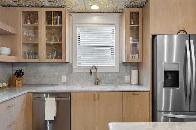 1307 E 2nd St, Austin, TX 78702 - kitchen with stainless steel appliances, a sink, decorative backsplash, glass insert cabinets, and light brown cabinets
