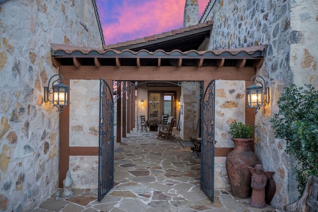 164 Camino Del Reserve, Comfort, TX 78013 - exterior entry at dusk featuring stone siding, a chimney, and a patio