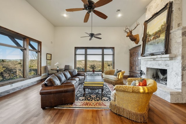 164 Camino Del Reserve, Comfort, TX 78013 - living room featuring a stone fireplace, ceiling fan, wood finished floors, a towering ceiling, and recessed lighting