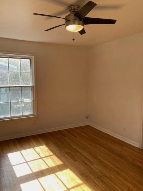 spare room featuring wood finished floors, a ceiling fan, and baseboards