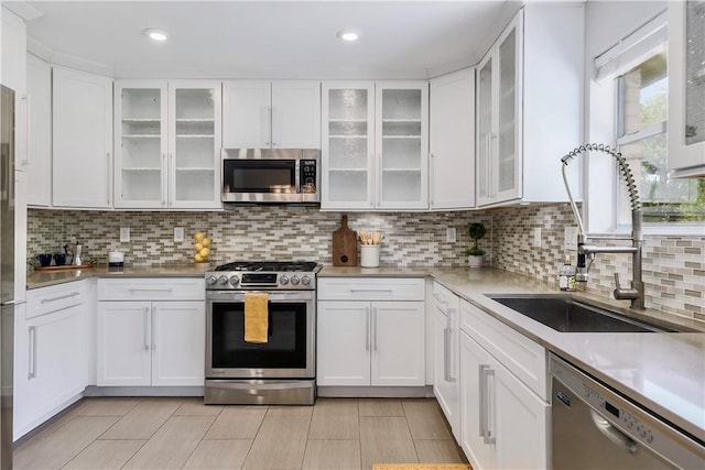 kitchen with stainless steel appliances, a sink, white cabinetry, decorative backsplash, and recessed lighting