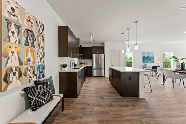 6444 Burnet Rd Unit 204, Austin, TX 78757 - kitchen featuring freestanding refrigerator, dark brown cabinetry, light countertops, a center island, and wood finished floors