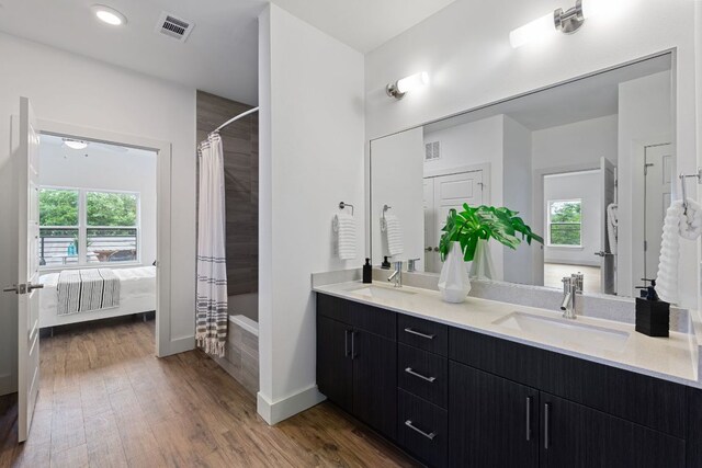 6444 Burnet Rd Unit 204, Austin, TX 78757 - ensuite bathroom featuring double vanity, healthy amount of natural light, wood finished floors, and tiled shower / bath