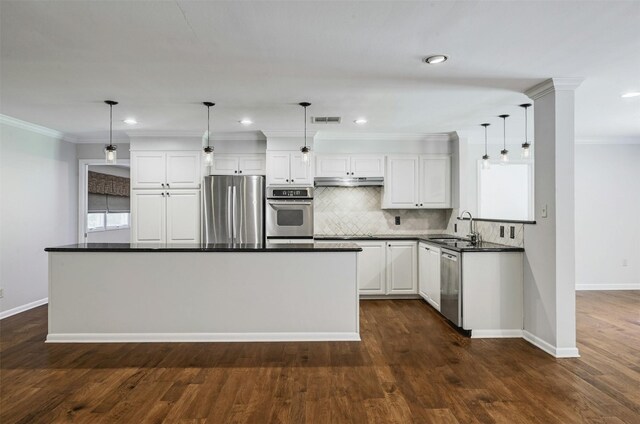 4905 Southcrest Dr, Austin, TX 78746 - kitchen featuring appliances with stainless steel finishes, dark countertops, ornamental molding, under cabinet range hood, and baseboards