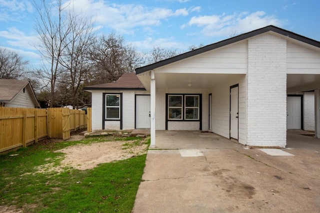 1317 Mckie Cv, Austin, TX 78752 - view of front facade featuring brick siding, fence, concrete driveway, and a carport