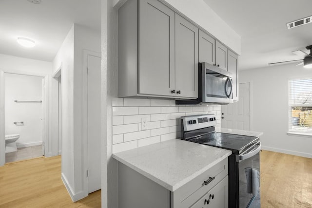1317 Mckie Cv, Austin, TX 78752 - kitchen with stainless steel appliances, gray cabinets, decorative backsplash, and ceiling fan